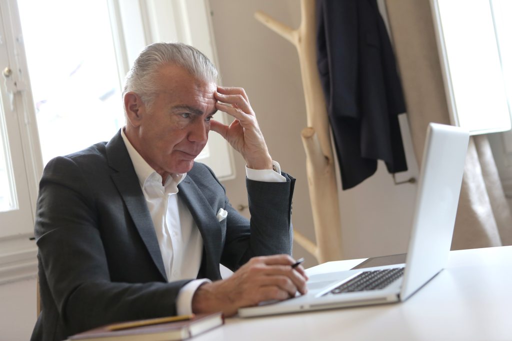 איש מבוגר עובד מול המחשב ומחזיק בראשו