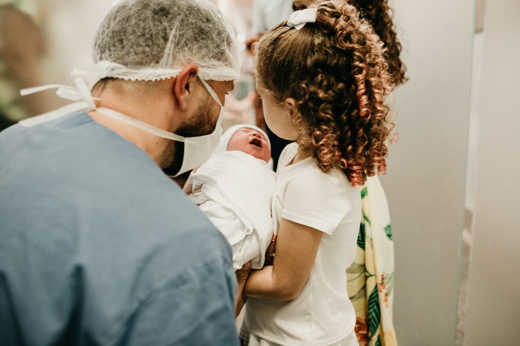 ידה קטנה מחזיקה תינוק שעכשיו נולד, ורופא משגיח עליהם