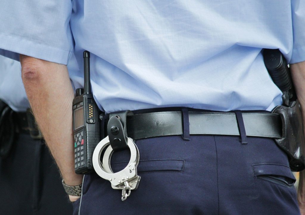 צילום מקרוב של חגורת שוטר, מכשיר קשר ואזיקים