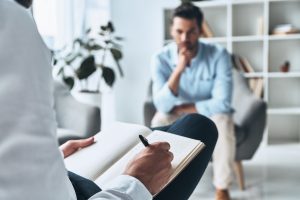 אדם יושב בטיפול והמטפל כותב במחברת